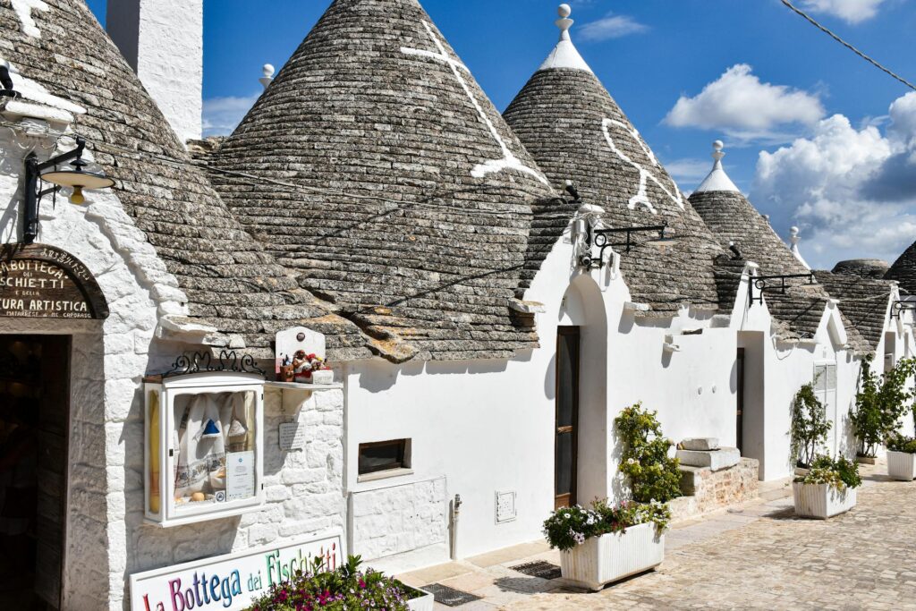 Trulli bianchi con tetti conici in pietra nel centro storico di Alberobello, sotto un cielo azzurro