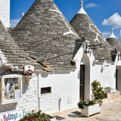 Trulli bianchi con tetti conici in pietra nel centro storico di Alberobello, sotto un cielo azzurro