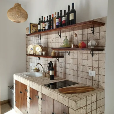 Cucina in pietra della Villa Agapanthus con scaffali in legno, piastrelle rustiche e prodotti tipici pugliesi