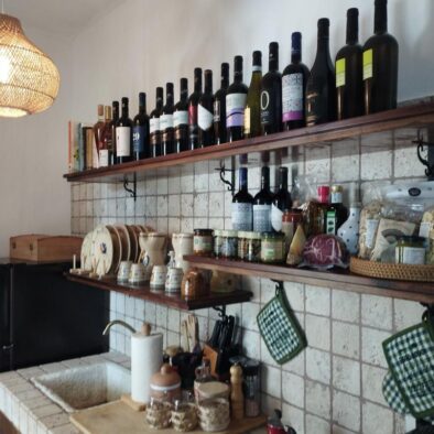 Cucina in pietra con scaffali di vini e oli pugliesi nella Villa Agapanthus, arricchita da dettagli artigianali e luce naturale