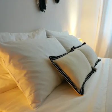 Cuscini bianchi su letto matrimoniale con luce calda e atmosfera rilassante nella camera della Villa Agapanthus