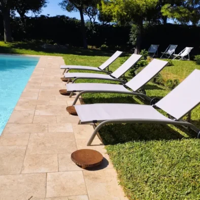 Lettini prendisole a bordo piscina nella villa con giardino a Monopoli