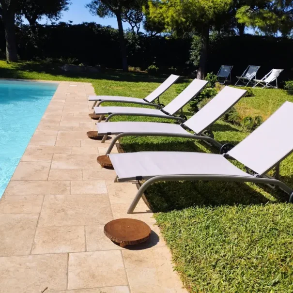Lettini prendisole a bordo piscina nella villa con giardino a Monopoli