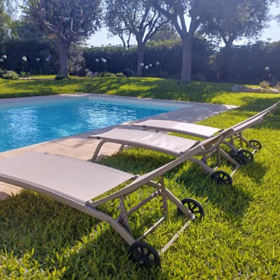 Lettini prendisole a bordo piscina nella villa con giardino a Monopoli