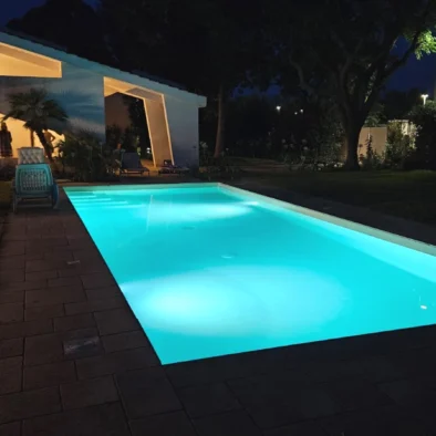 Piscina privata della Villa Agapanthus illuminata di notte, con riflessi azzurri e atmosfera elegante nel giardino pugliese