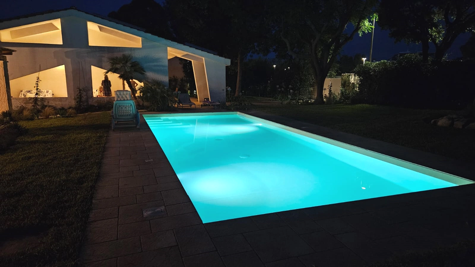 Piscina privata della Villa Agapanthus illuminata di notte, con riflessi azzurri e atmosfera elegante nel giardino pugliese