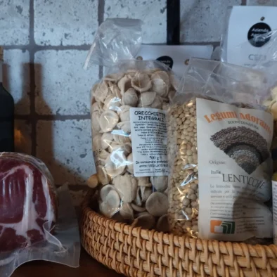 Prodotti tipici pugliesi su mensola rustica: pasta artigianale, salumi, vino, olio e conserve nella cucina della villa