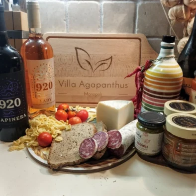 Selezione di prodotti tipici pugliesi con vino, salumi, formaggio, conserve, pasta e pomodorini nella cucina della villa