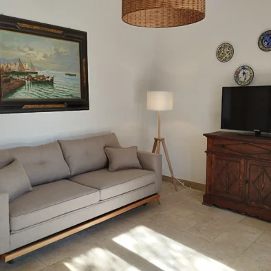 Divano con lampada da terra e quadro marinaro nel salotto della Villa Agapanthus, illuminato dalla luce del sole