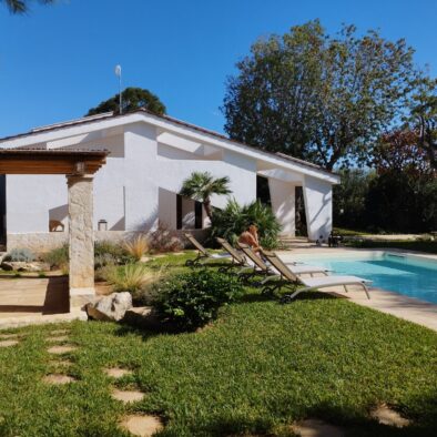 Vista panoramica della Villa Agapanthus con piscina privata, giardino curato, pergolato in legno e lettini prendisole
