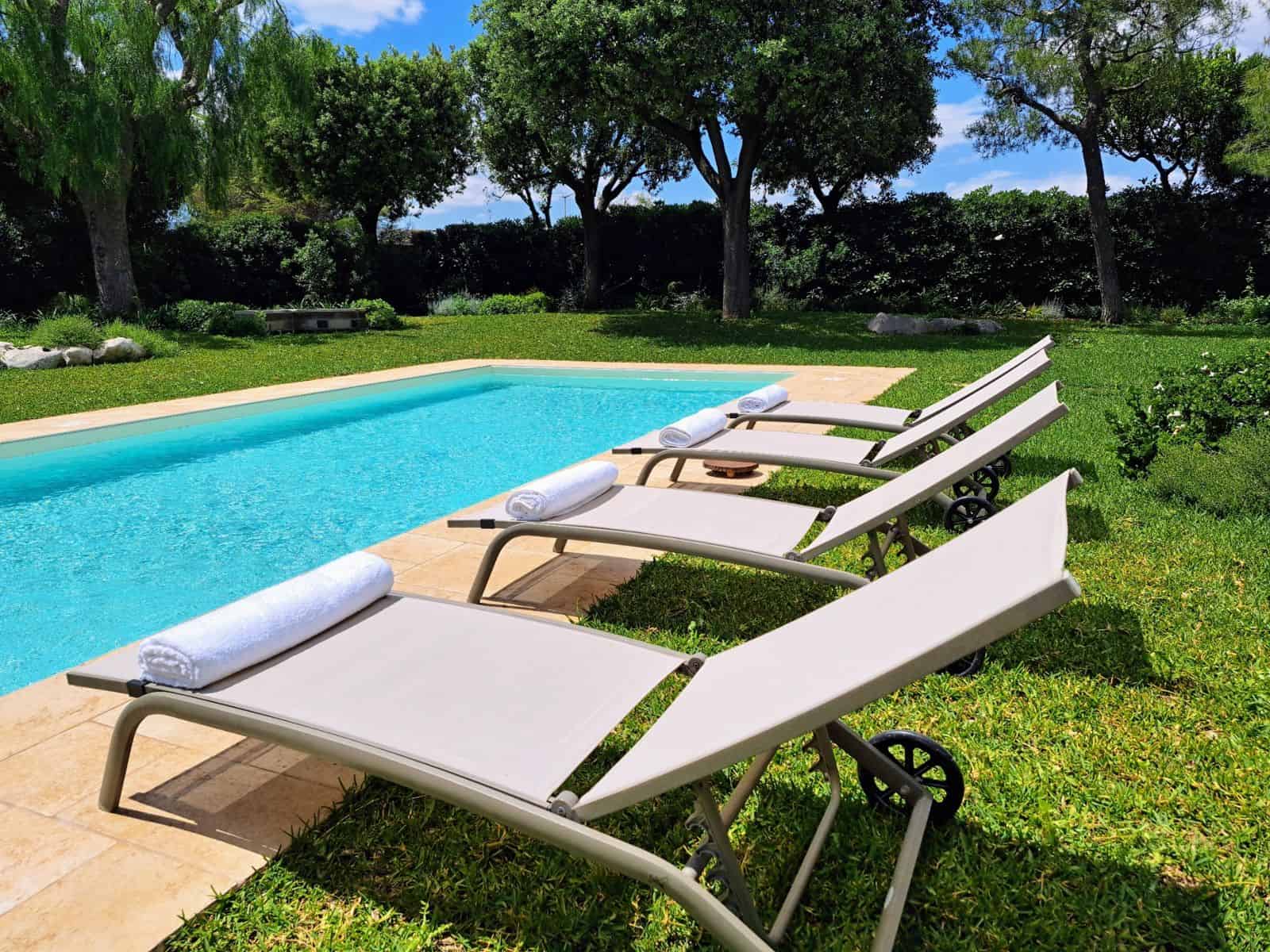 Lettini a bordo piscina nella villa con giardino a Monopoli